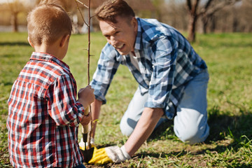 Father and son scooping soil in garden