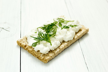 Breakfast with cottage cheese and green dill on a white wooden table.