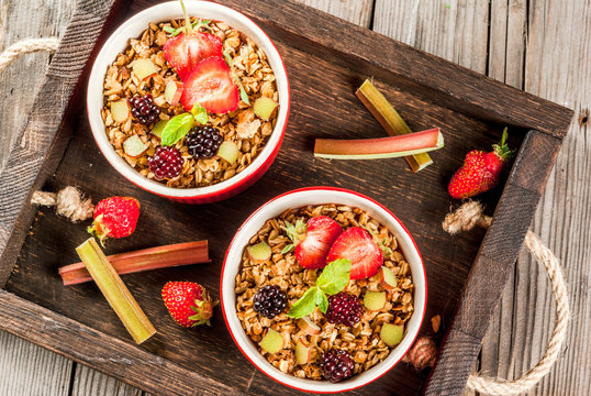 Healthy Breakfast. Oatmeal Granola Crumble With Rhubarb, Fresh Strawberries And Blackberries, Seeds And Ice Cream In Baked Bowls, Decorated With Mint, On A Wooden Rustic Table In Old Tray, Top View