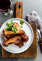 Pork ribs on white plate with chili sauce on slate background