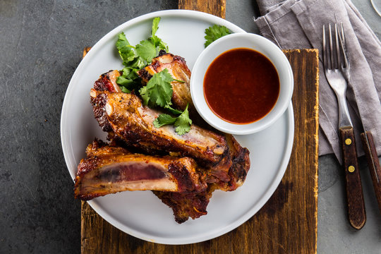 Pork ribs on white plate with chili sauce