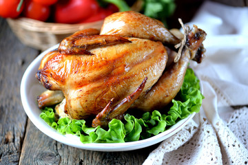 Baked chicken with olive oil and soy sauce and fresh vegetables on an old wooden background.