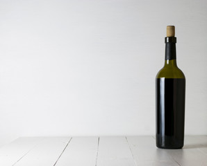 Red wine bottle and corkscrew on white wooden table background with copy space