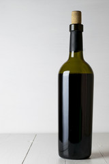 Red wine bottle and corkscrew on white wooden table background with copy space