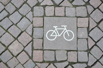 A sign of a bicycle path on a square stone - obrazy, fototapety, plakaty
