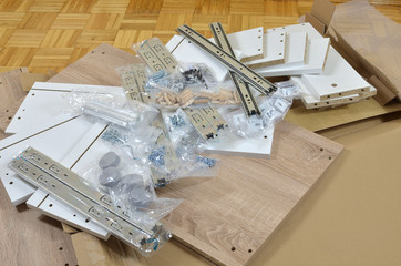 Pile of just unpacked elements of a new chest of drawers ready for assembling