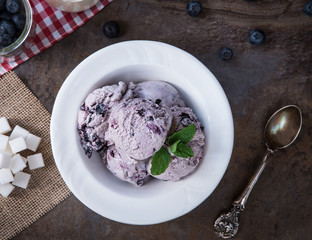 Blueberry homemade ice cream with mint leaves and Spoon for ice cream on stone slate background