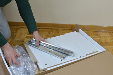 Unpacking a box of a new piece of furniture taking out drawer rails