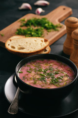 Homemade cold beetroot soup on black background.