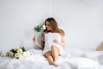 Obraz na płótnie Canvas Pregnant girl with tattoo in a white dress.