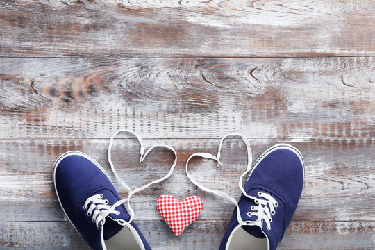 Blue sport shoes with red heart on grey wooden table