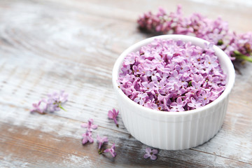Obraz na płótnie Canvas Lilac flowers in bowl on wooden table
