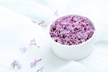 Fototapeta na wymiar Lilac flowers in bowl on white cloth