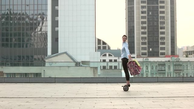 Young woman with shopping bags. Lady on hoverboard, side view.
