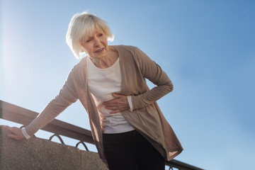 Fototapeta premium Old woman feeling stomachache outside