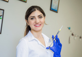 Beautiful doctor in blue gloves with anesthetic aspirating syringe. Dentist nurse. Cosmetology. Dentist prick. Dental tools