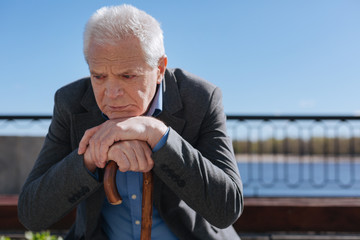 Aged pensioner thinking about mistakes of his past near the lake