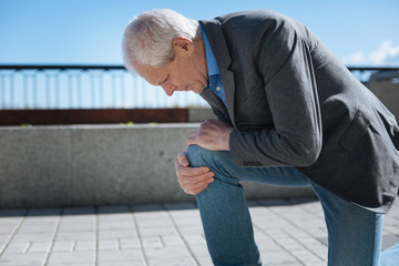 Concentrated pensioner suffering from knee ache in the park