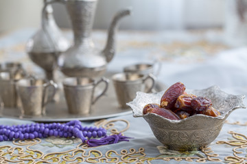 Dates with zam zam water cups background with purple rosary on white table cloth
