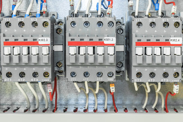 On the artboard mounted three electric contactor with auxiliary contacts. The contactors connected wires with ferrules and marking.
