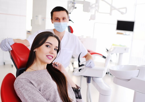 Young beautiful girl in dental chair on background of dentist smiling at camera. Dentistry, snow-white smile, beauty,