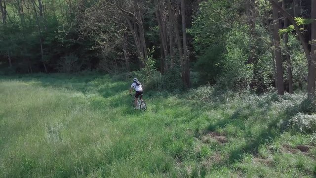 MTB bike riding on track trail in springtime forest, Italy, Europe. Follow shot Aerial 4k UHD native log movie (3840X2160).
