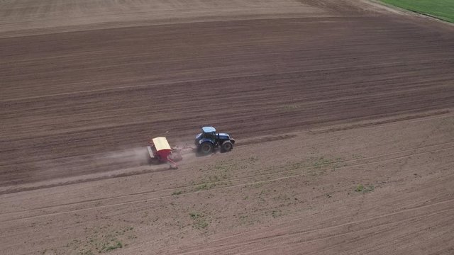 Cinematic aerial footage by tractor seeding the field