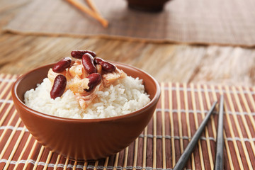 Bowl with tasty chicken, rice and beans on wicker mat