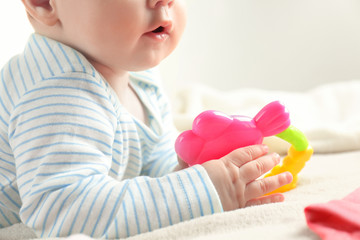 Obraz na płótnie Canvas Cute baby holding toy rattle on bed, closeup
