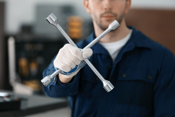 Auto mechanic with wheel wrench in car repair shop