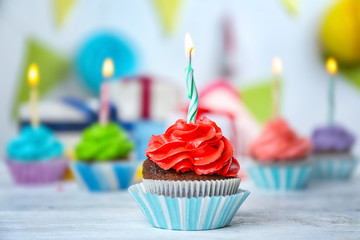 Delicious cupcake with lighted candle on festive background