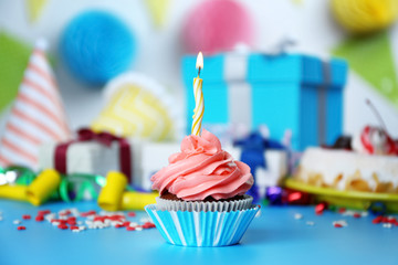 Delicious cupcake with lighted candle on festive background