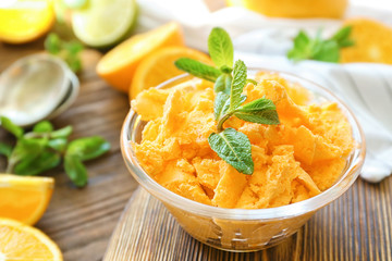 Glass bowl with delicious citrus ice cream on wooden board