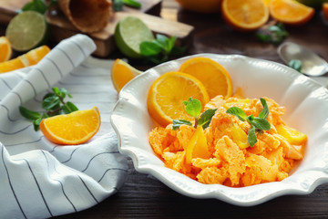 Plate with delicious citrus ice cream on wooden table