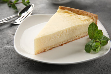 Plate with piece of tasty cheesecake on grey table, closeup