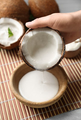 Woman pouring coconut cream into bowl on table