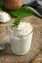 Delicious coconut cream in glass on wooden background