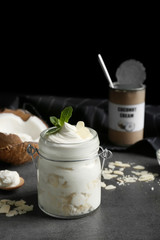 Delicious coconut cream in jar on dark background