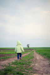 little child standing at the beginning of straight road going to horizon