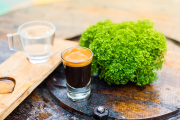 Espresso coffee cup serve with glass of water on wooden table