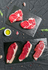 Beef cow steak meat with spices and herbs against black background