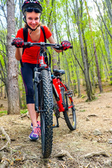 Bikes bicyclist girl wearing helmet and big backpack cycle bicycle into forest. Cycling is good for health. Cyclist looking at camera. Hike on bicycles.
