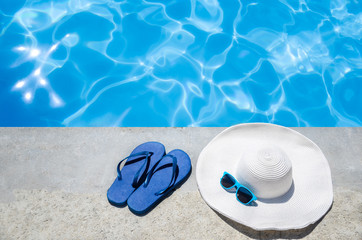 Fototapeta na wymiar Summer background with hat, flip flops and sunglasses near the pool