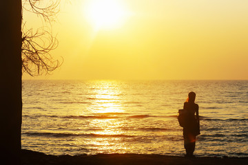Female silhouette against bright sea sunset on horizon line