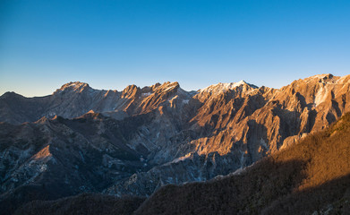 Apuane alpi snowy mountains and marble quarry at sunset in winter. Carrara, Tuscany, Italy.