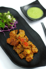 Braised pork with chili sauce and salad on black platter