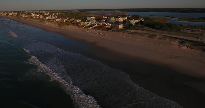 An early morning forward aerial establishing shot of the houses along Topsail Island on the Atlantic Ocean in North Carolina.	 	