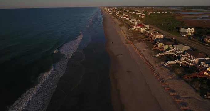 An early morning rising aerial establishing shot of the houses along Topsail Island on the Atlantic Ocean in North Carolina.	 	