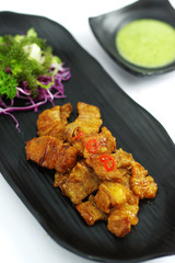 Braised pork with chili sauce and salad on black platter