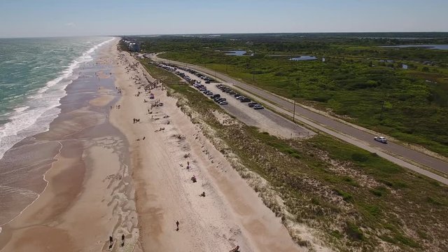A daytime reverse aerial establishing shot of the beach at Topsail Island, North Carolina.  	